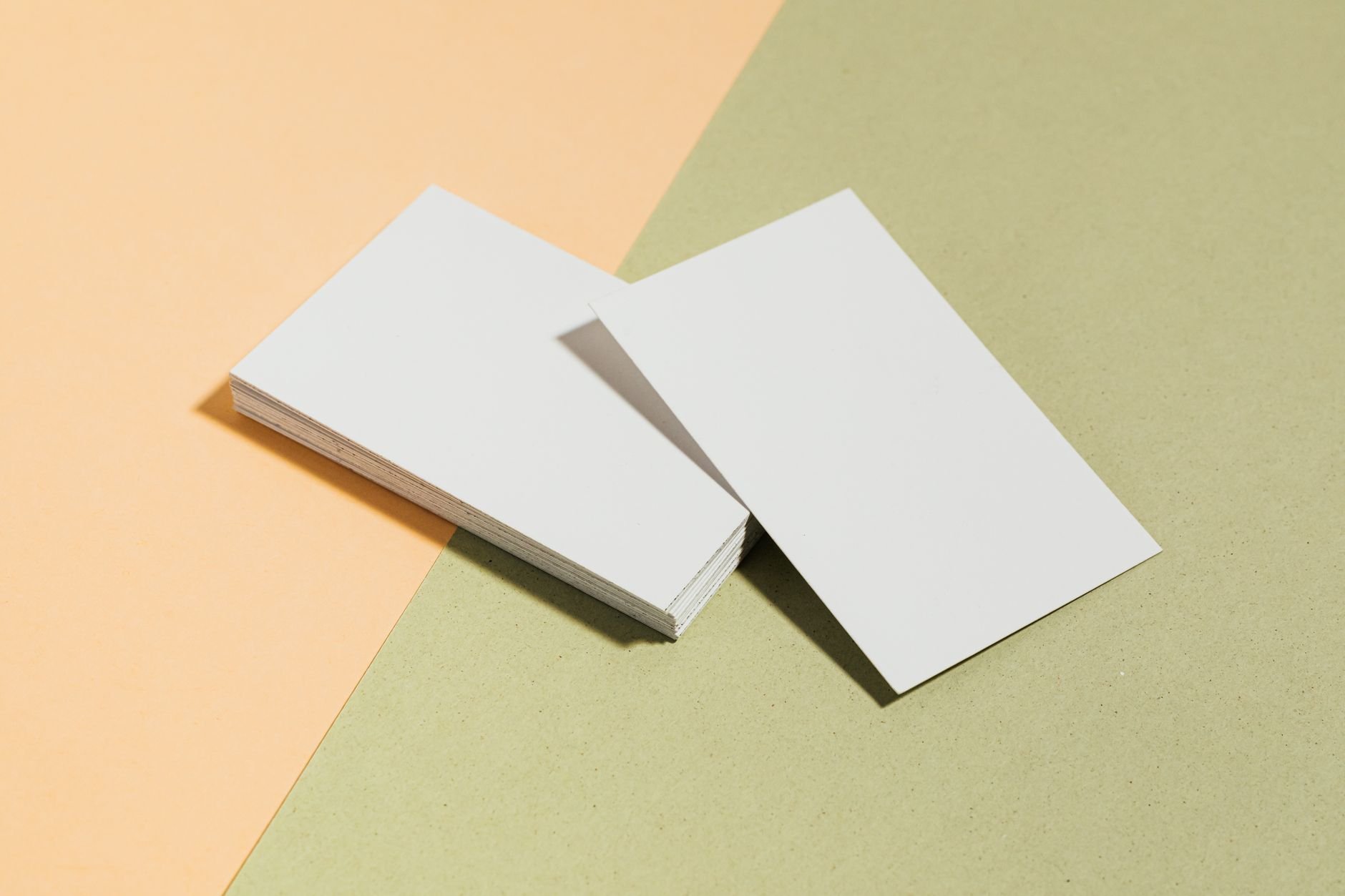 Stack of blank white business cards on pastel surface — print design mockup